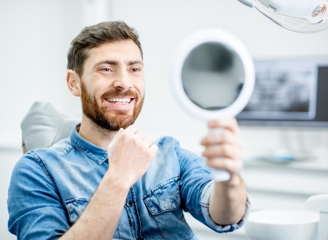 Dental patient seeing his new smile in a mirror