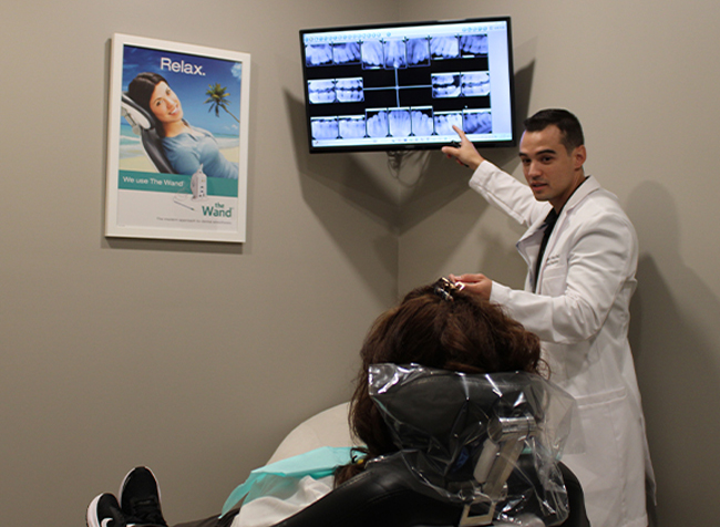 Doctor Perez pointing to dental x rays in front of a patient