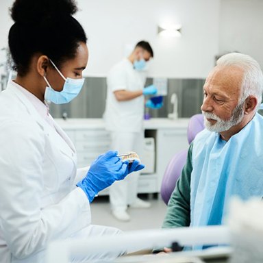 a dentist showing dentures to a patient