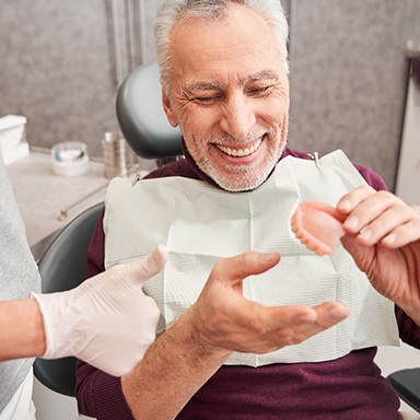 Man holding a denture and smiling