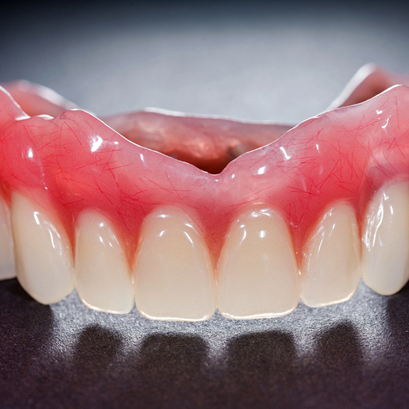 Close up of a denture on a gray surface