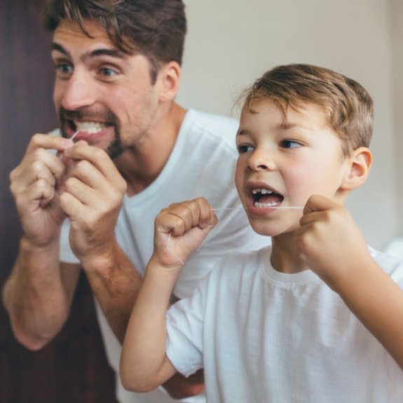 Father and son flossing their teeth together