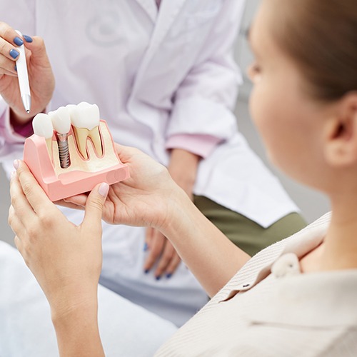 Dentist showing patient model of dental implant