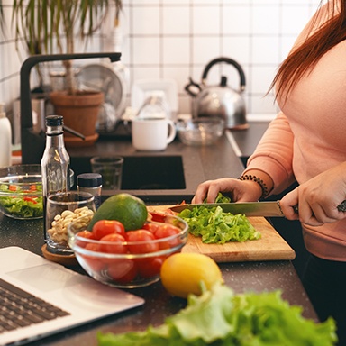 Woman chopping fresh vegetables in kitchen