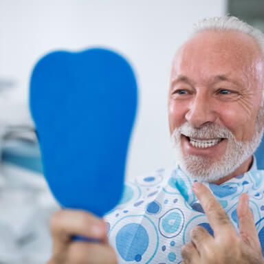 a dental patient admiring his smile in a mirror 