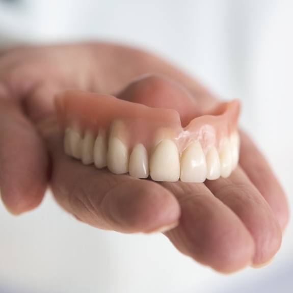 Hand holding a full upper denture