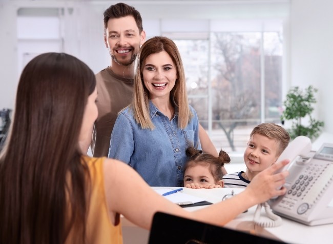 Family of four smiling at front desk receptionist